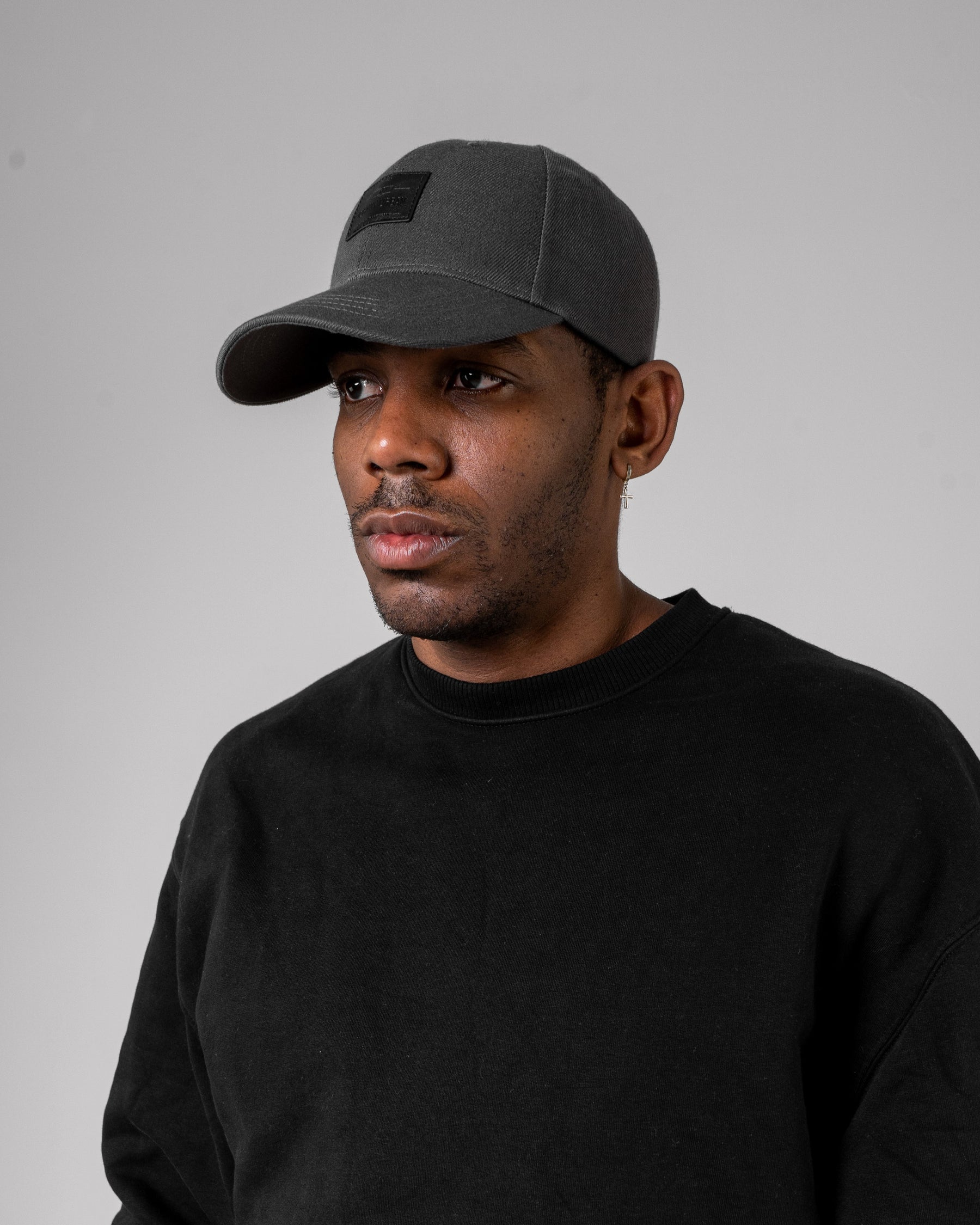 Mann trägt graue, gebogene Cap 'Dean' von Johnny Urban und schwarzen Pullover