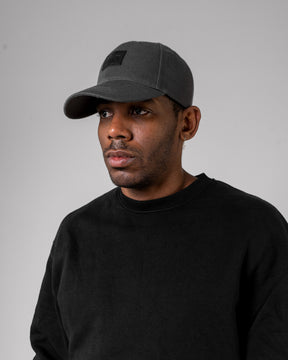 Mann trägt graue, gebogene Cap 'Dean' von Johnny Urban und schwarzen Pullover