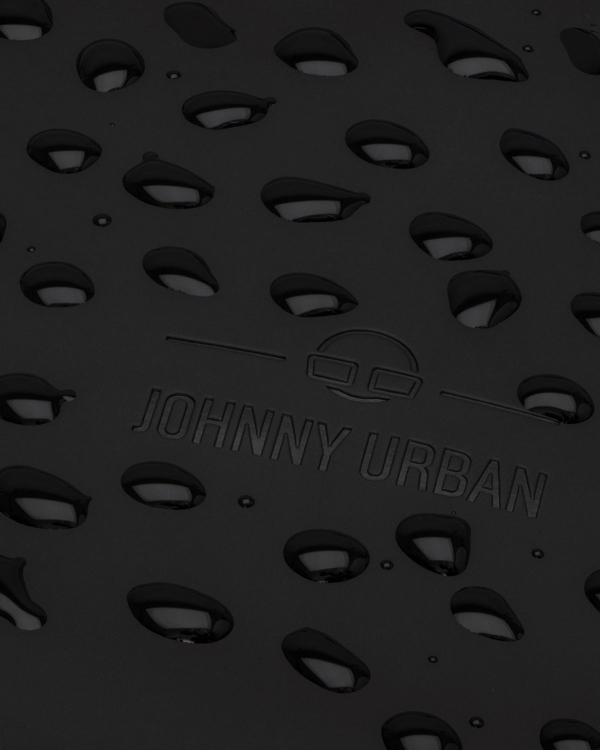 Nahaufnahme des schwarzen, regenfesten Rucksacks 'Hailey' mit JOHNNY URBAN Logo und Wasserperlen auf Oberfläche