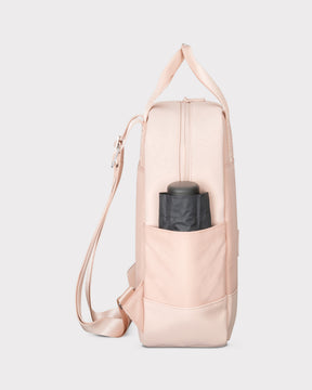 Rucksack 'Jona Small' in rosa mit seitlicher Außentasche, die einen schwarzen Gegenstand hält