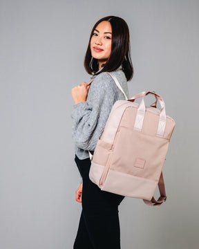 Frau trägt den rosa Damenrucksack 'Jona Large' von Johnny Urban über einem grauen Pullover