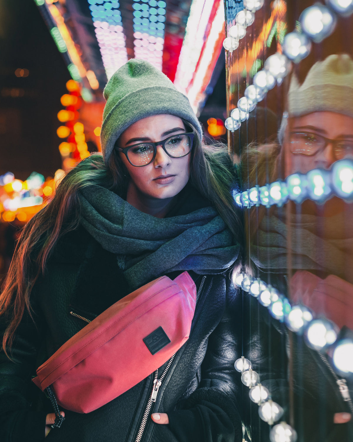 Frau mit Brille, grauer Mütze und Schal trägt rote Bauchtasche 'Tom' von Johnny Urban bei Nacht