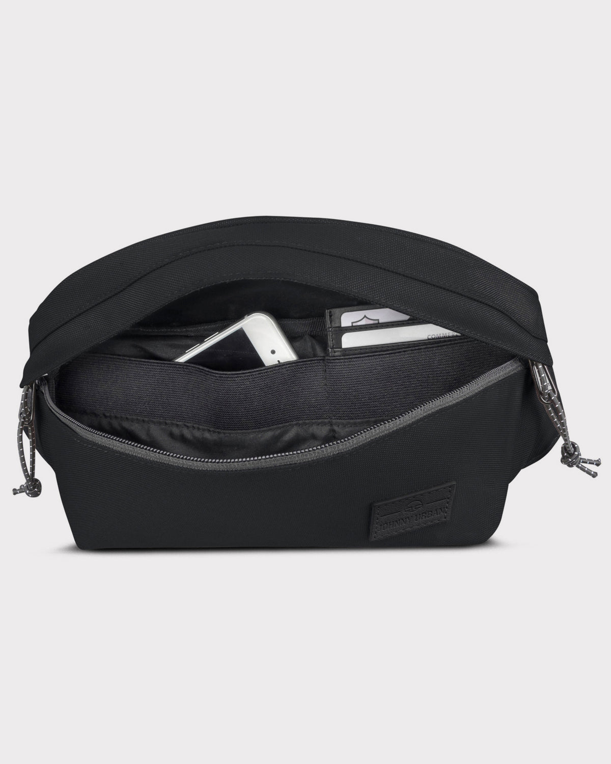 Schwarze Bauchtasche 'Tom' von Johnny Urban mit geöffnetem Reißverschluss, sichtbar Innenfächer mit Handy und Karten