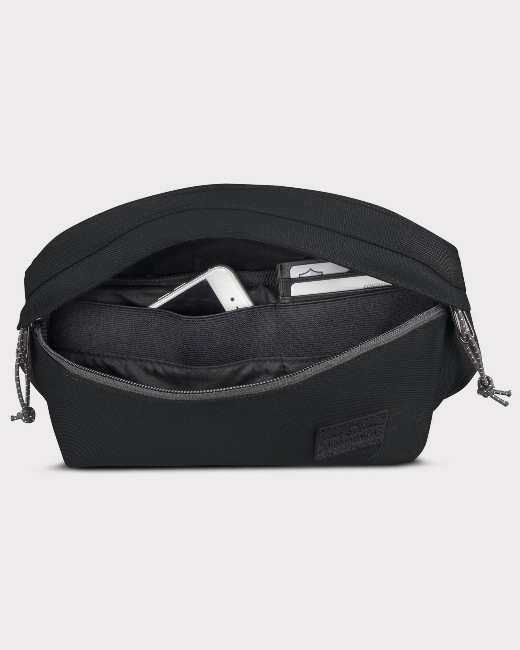 Schwarze Bauchtasche 'Tom' von Johnny Urban mit geöffnetem Reißverschluss, sichtbar Innenfächer mit Handy und Karten