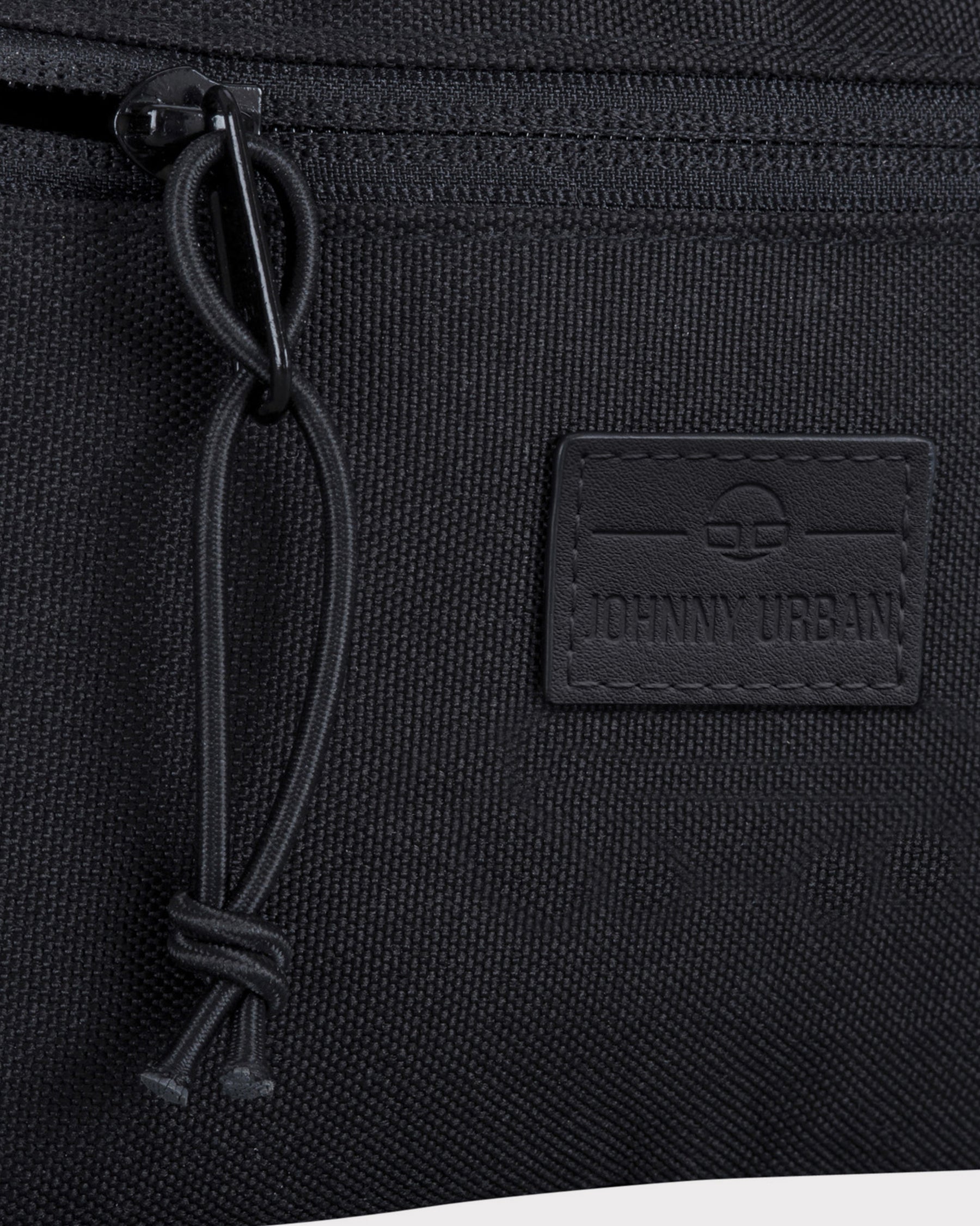 Nahaufnahme der schwarzen Bauchtasche 'Erik Small' von Johnny Urban mit Reißverschluss und Logo-Patch