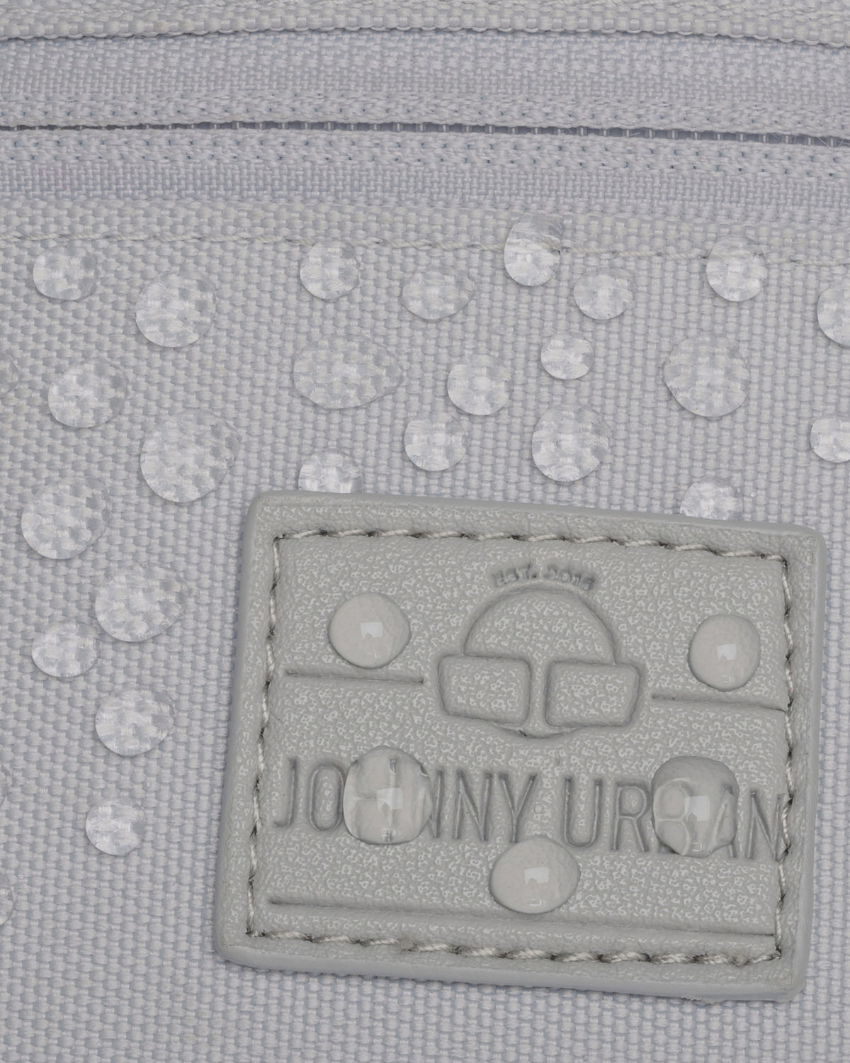 Nahaufnahme des wasserabweisenden Materials und des Logos der grauen Bauchtasche 'Erik Small' von Johnny Urban