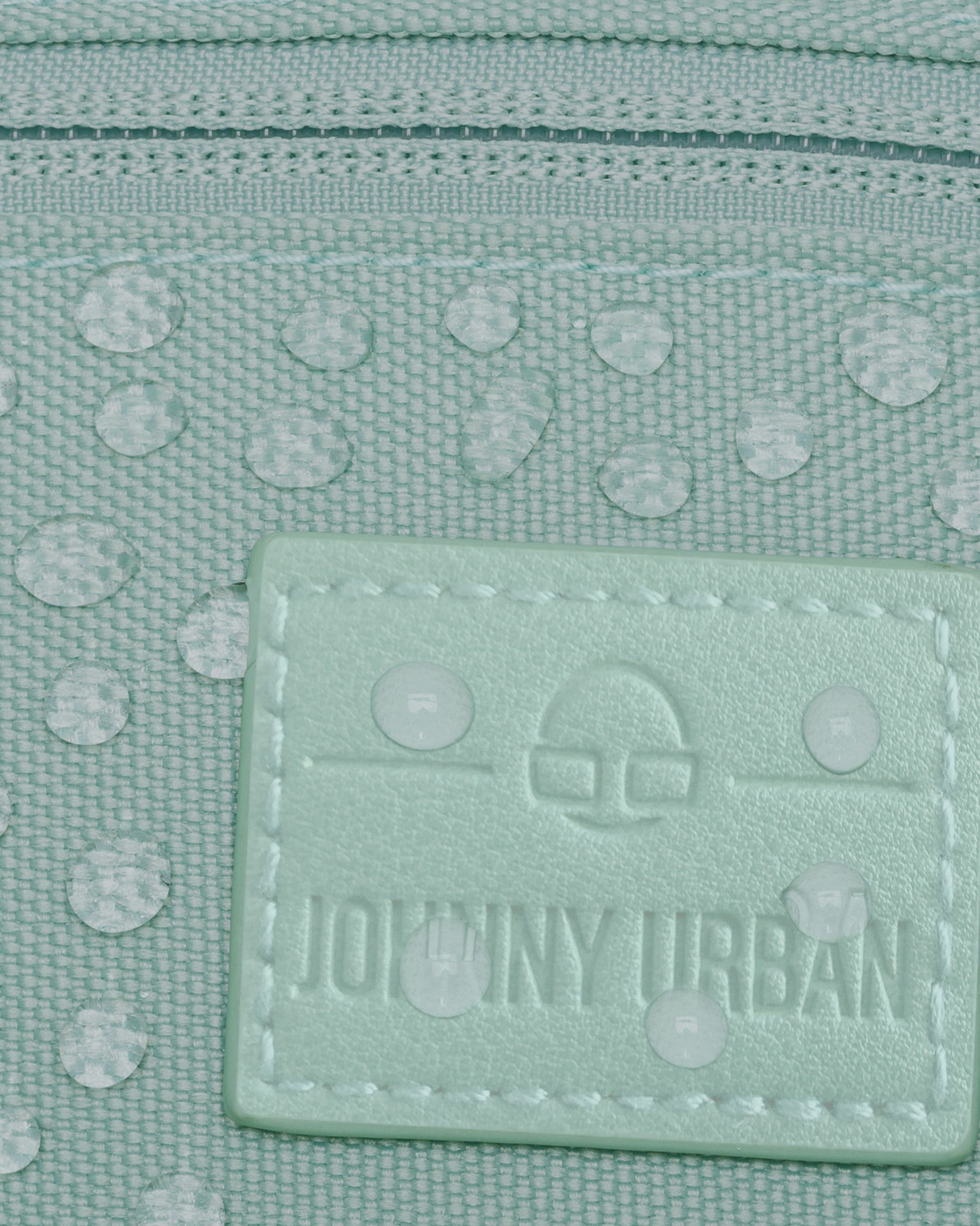 Mintgrüne, wasserabweisende Bauchtasche 'Erik Small' von Johnny Urban mit Logoetikett und Wassertropfen auf dem Material