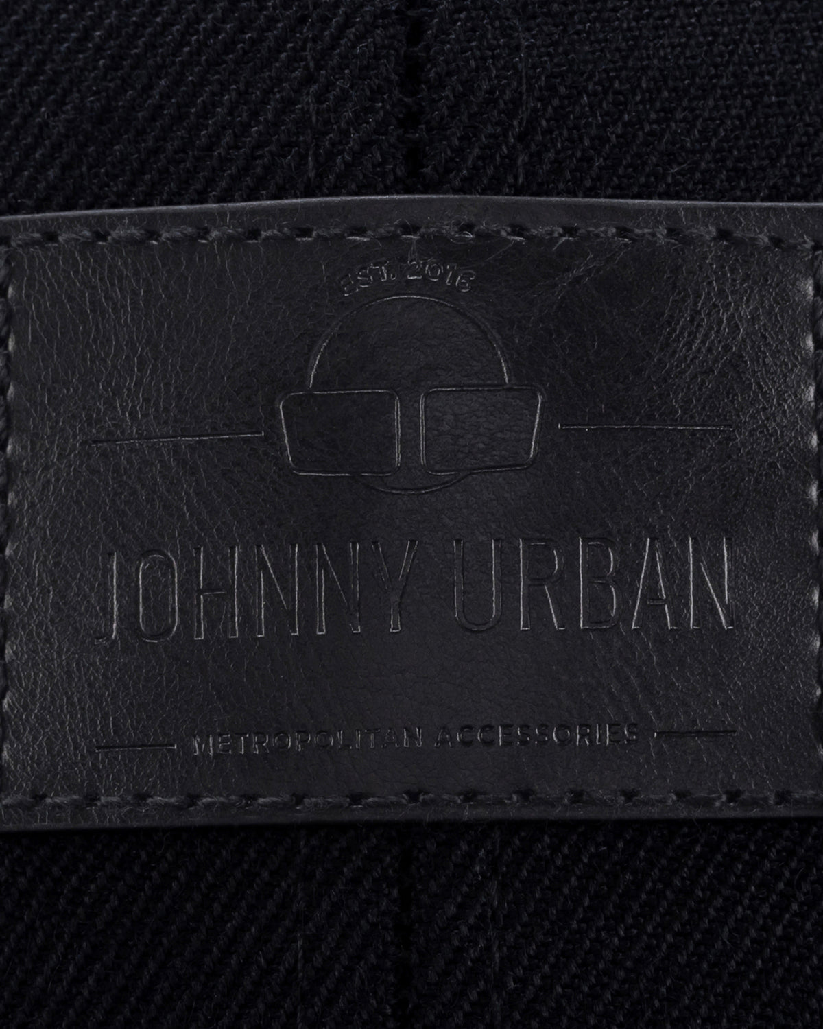 Schwarzes Lederetikett mit eingeprägtem Logo und Text 'Johnny Urban', auf dunklem Stoff mit sichtbarer Naht