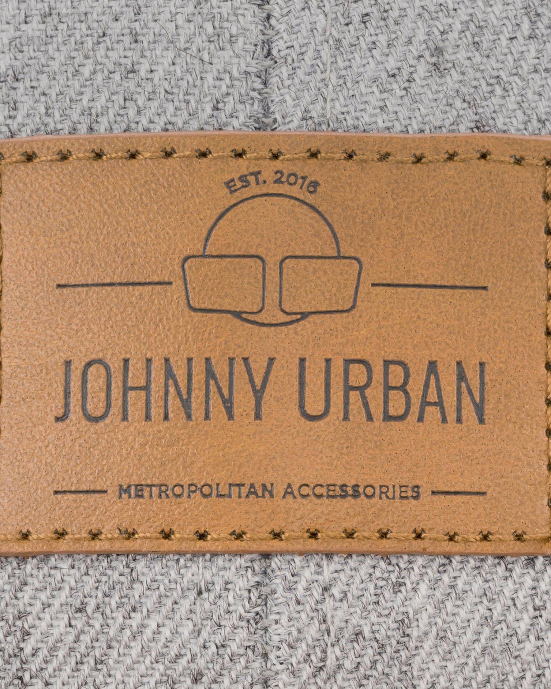 Nahtloses braunes Lederetikett mit Johnny Urban-Logo und Schriftzug auf grauer Textilstruktur