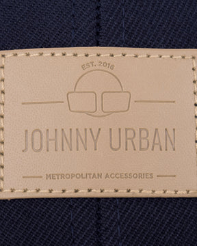 Beige geprägtes Lederetikett mit 'Johnny Urban', 'EST. 2016' und 'Metropolitan Accessories' auf dunkelblauem Stoff