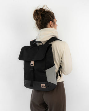 Rucksack 'Mika' von Johnny Urban in Schwarz mit grauen Details, getragen von einer Frau mit beigem Pullover und braunen Hosen