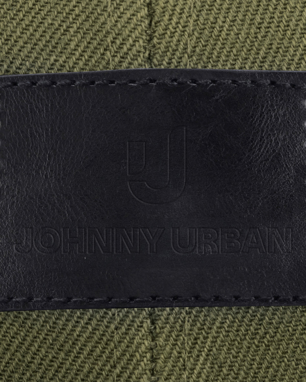 Schwarzes Lederlabel mit eingeprägtem Johnny Urban Logo und Text auf grünem Stoff