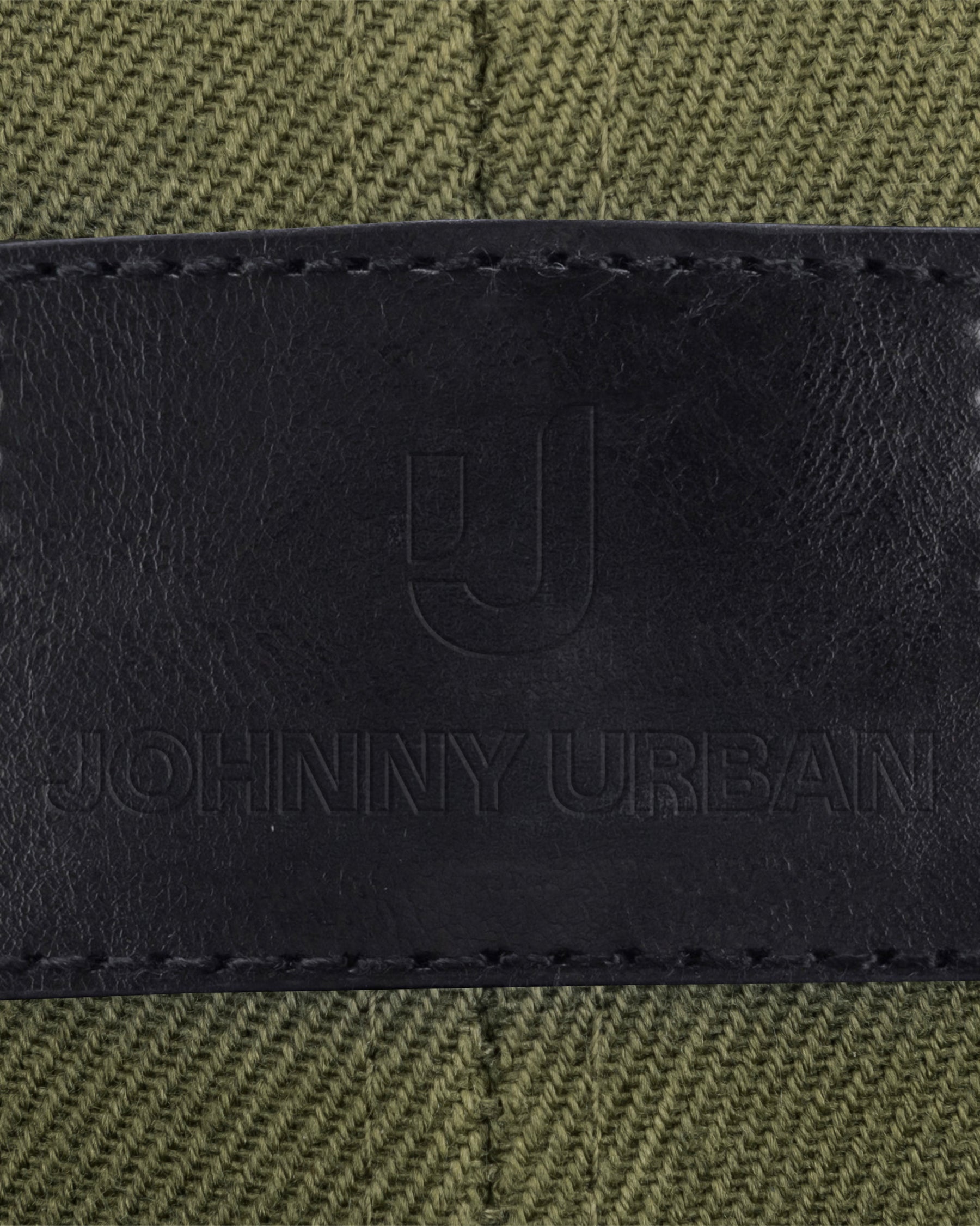 Schwarzes Lederlabel mit eingeprägtem Johnny Urban Logo und Text auf grünem Stoff