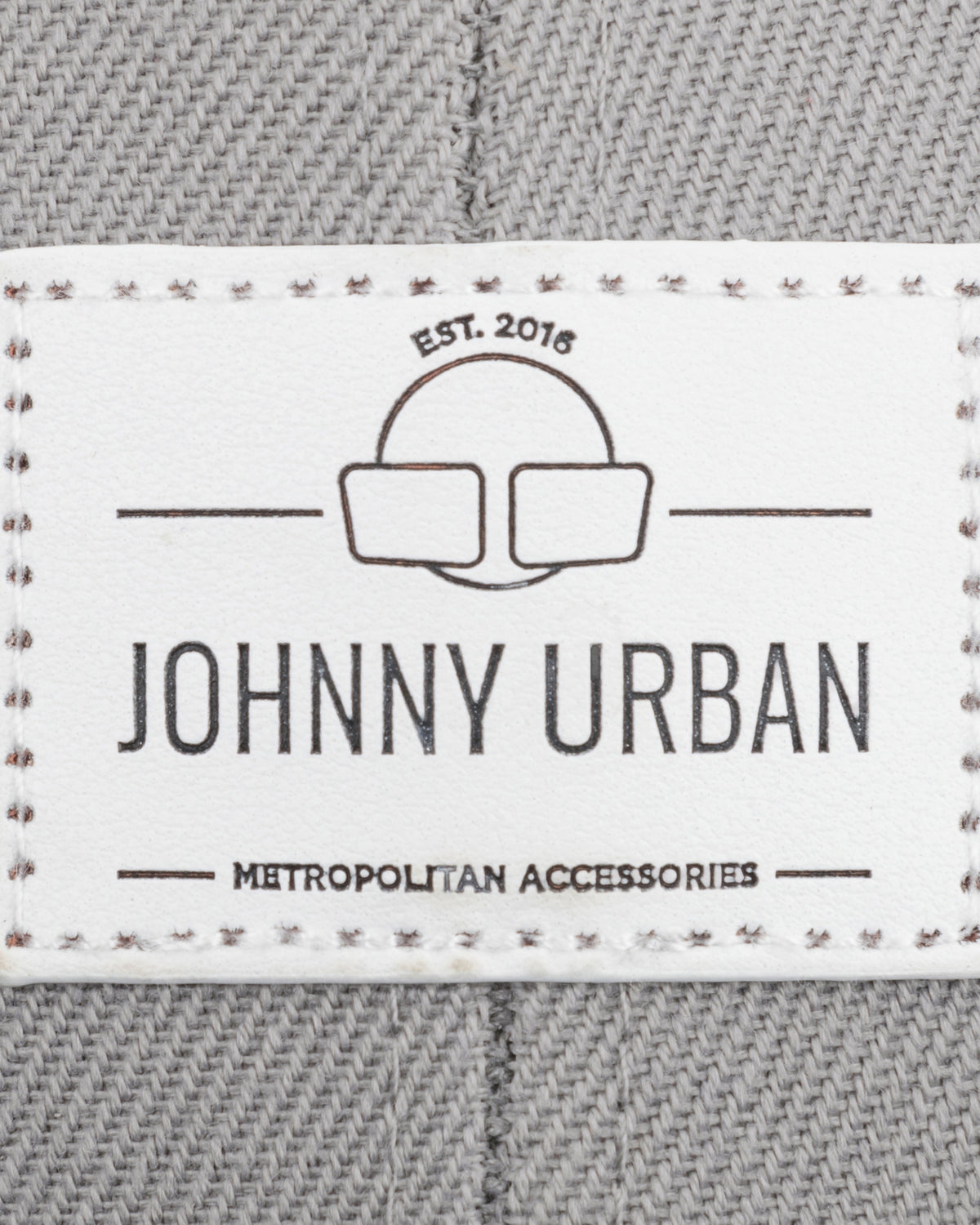 Johnny Urban Logoetikett mit 'EST. 2016' und 'METROPOLITAN ACCESSORIES' auf grauem Stoff