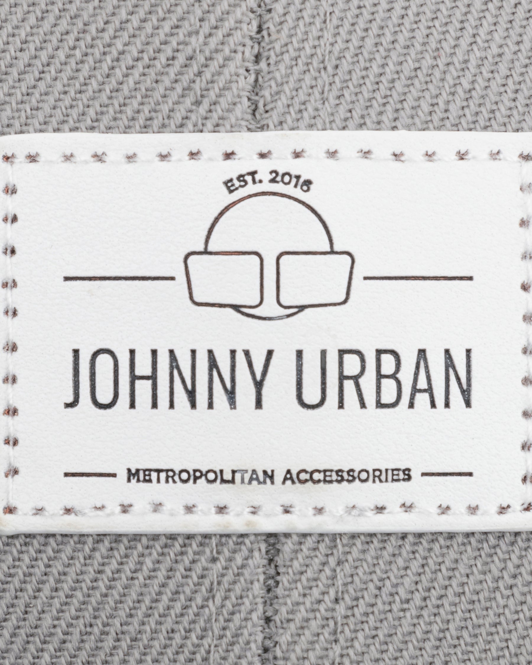 Johnny Urban Logoetikett mit 'EST. 2016' und 'METROPOLITAN ACCESSORIES' auf grauem Stoff
