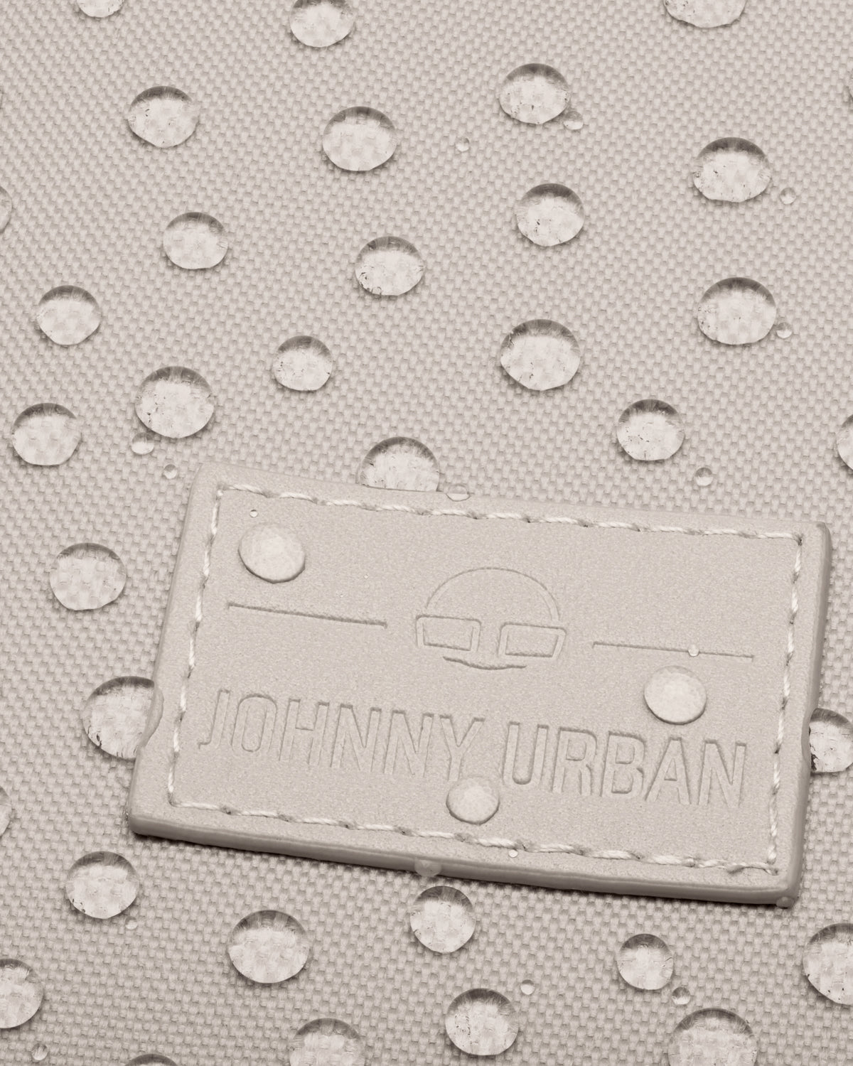 Nahe Nahaufnahme des wasserdichten Materials des Johnny Urban Rolltop Rucksacks "Robin Medium" mit aufgenähtem Logo