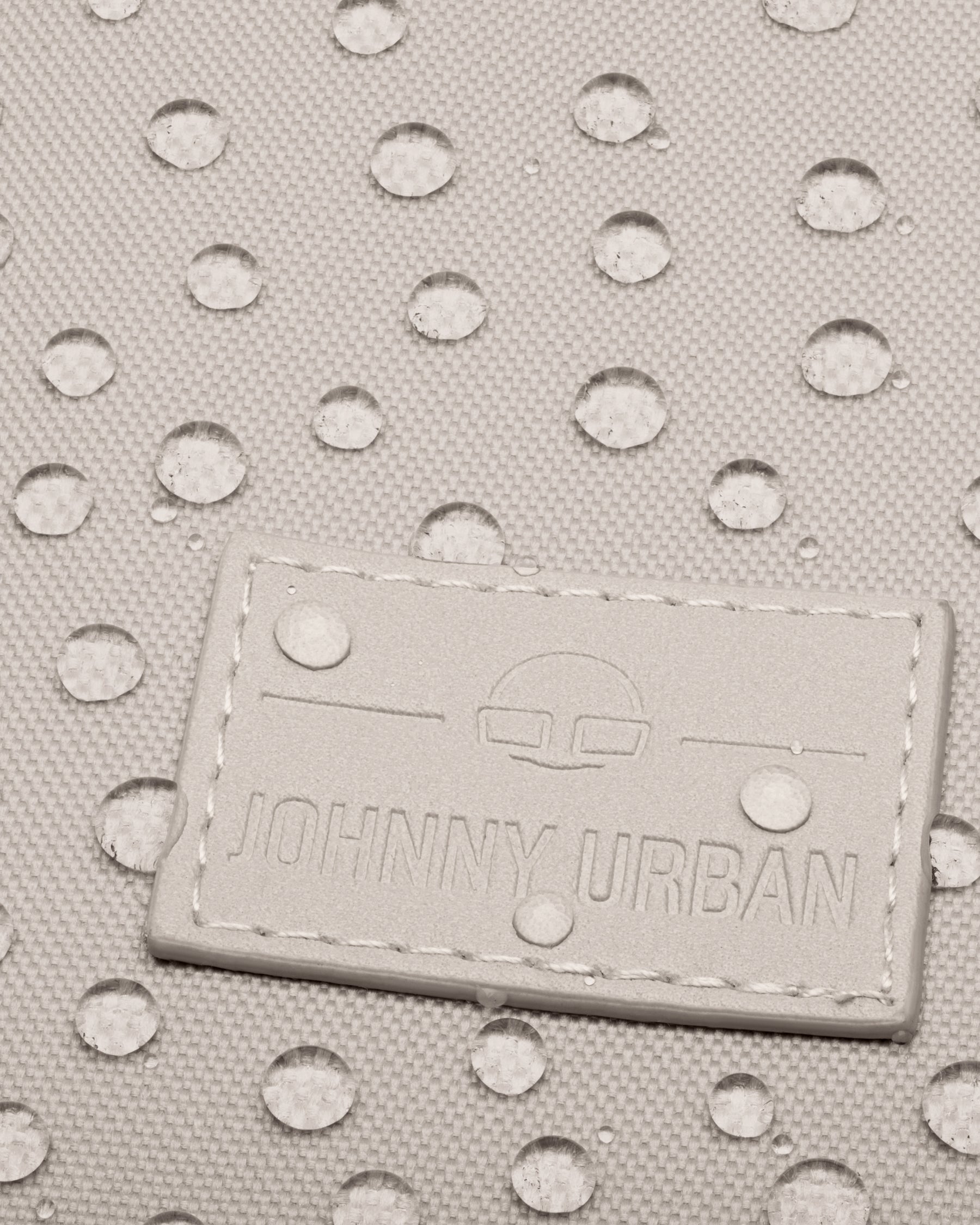 Nahe Nahaufnahme des wasserdichten Materials des Johnny Urban Rolltop Rucksacks "Robin Medium" mit aufgenähtem Logo