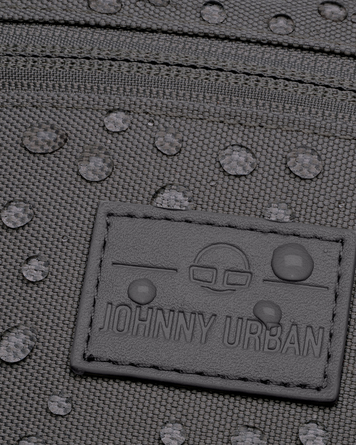 Nahaufnahme der wasserabweisenden, dunkelgrauen Bauchtasche 'Erik Small' von Johnny Urban mit sichtbaren Wassertropfen