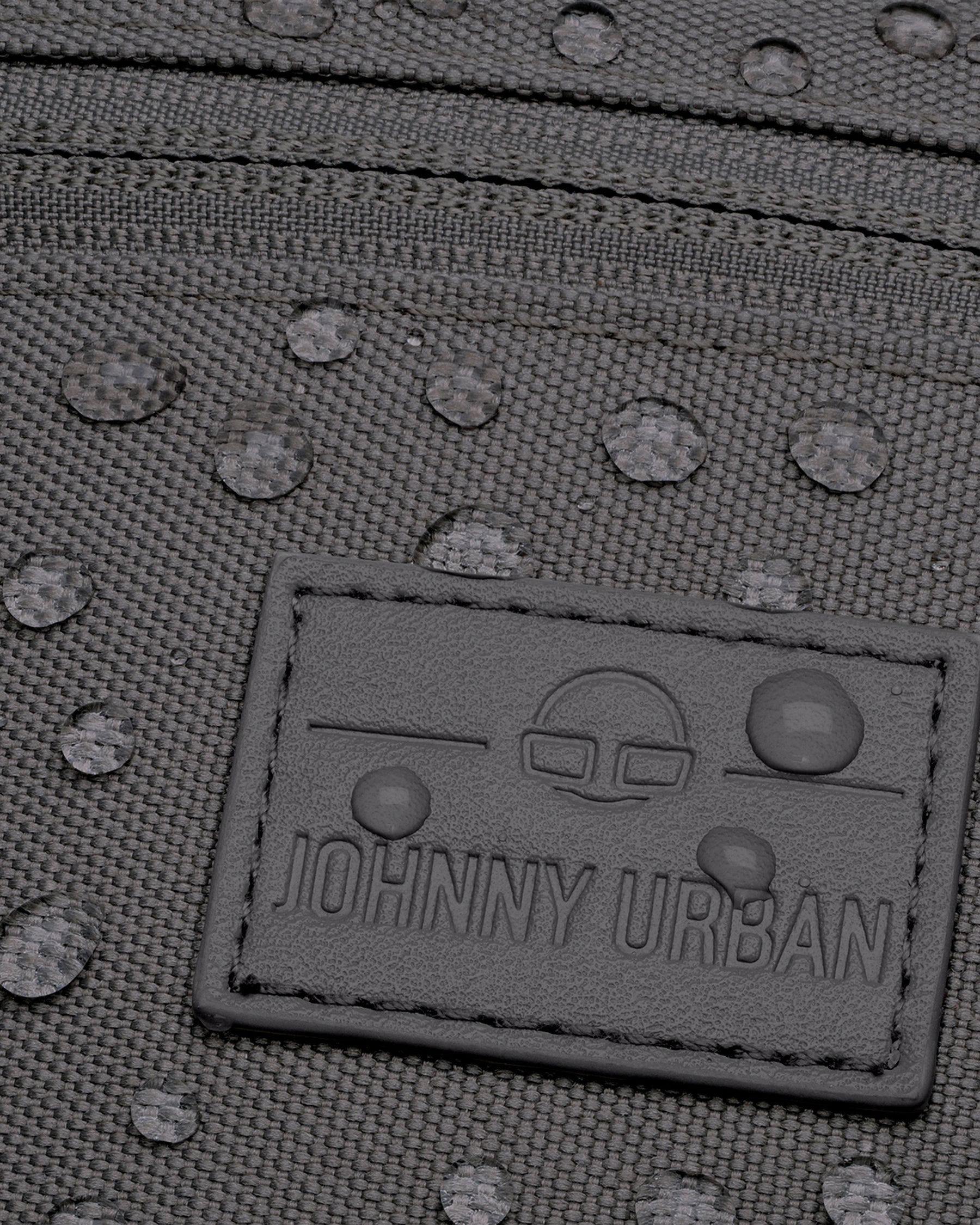 Nahaufnahme der wasserabweisenden, dunkelgrauen Bauchtasche 'Erik Small' von Johnny Urban mit sichtbaren Wassertropfen