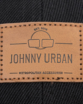 Nahaufnahme eines braunen, rechteckigen Johnny Urban Lederlabels mit gesticktem Rand auf schwarzem Stoff