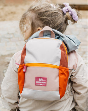Kinderrucksack 'Leo' in Beige, Orange und Braun getragen von einem Mädchen mit hellbraunem Haar und lilafarbenem Haargummi