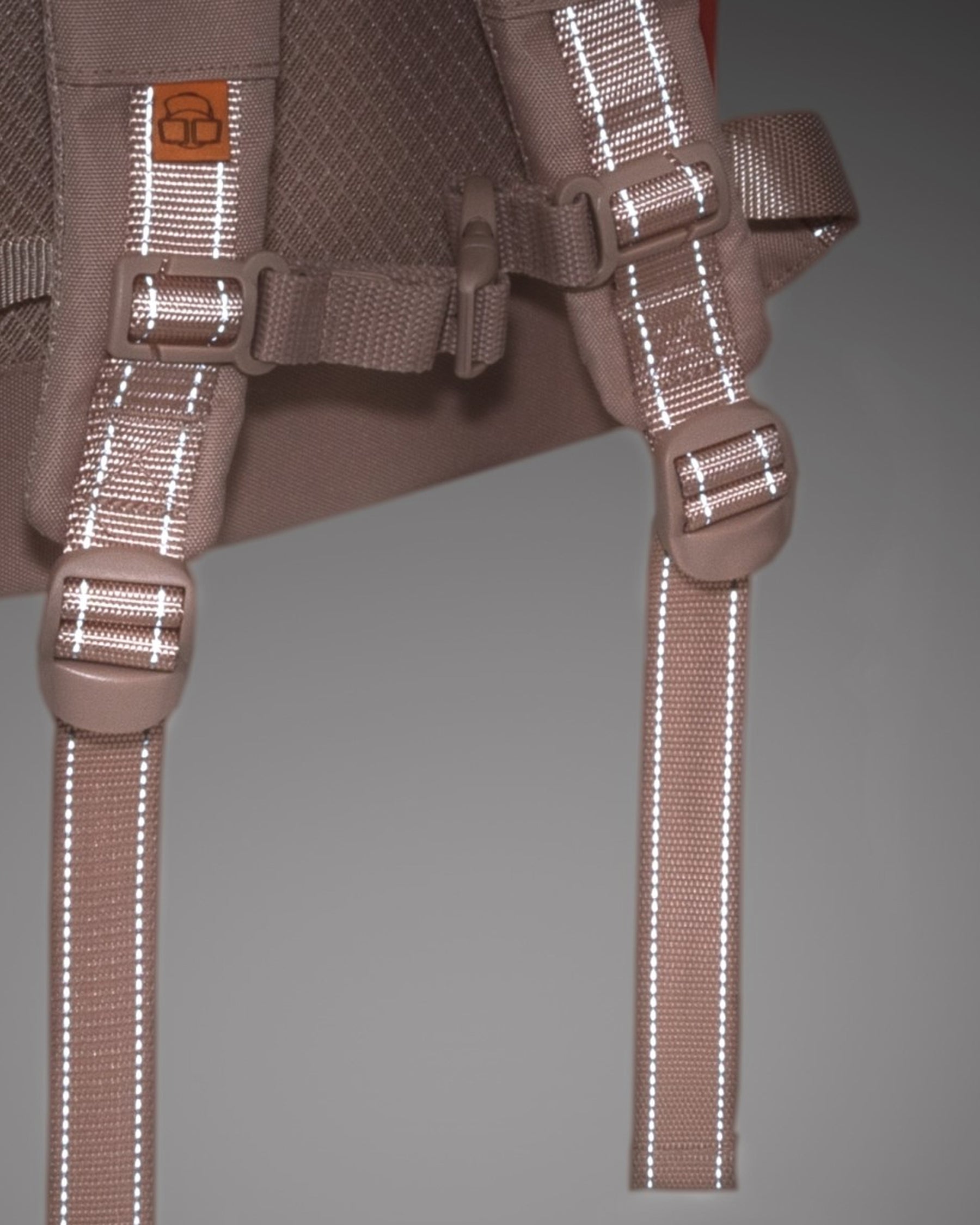 Nahaufnahme der verstellbaren Schultergurte des Kinderrucksacks 'Linus' mit reflektierenden Streifen und brauner Polsterung
