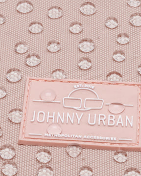 Nahaufnahme des JOHNNY URBAN Logos auf einem rosa wasserdichten Damenrucksack Romy mit Wassertropfen