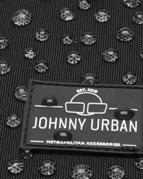 Nahaufnahme des Johnny Urban Logos auf wasserdichtem schwarzen Gewebe mit Wasserperlen
