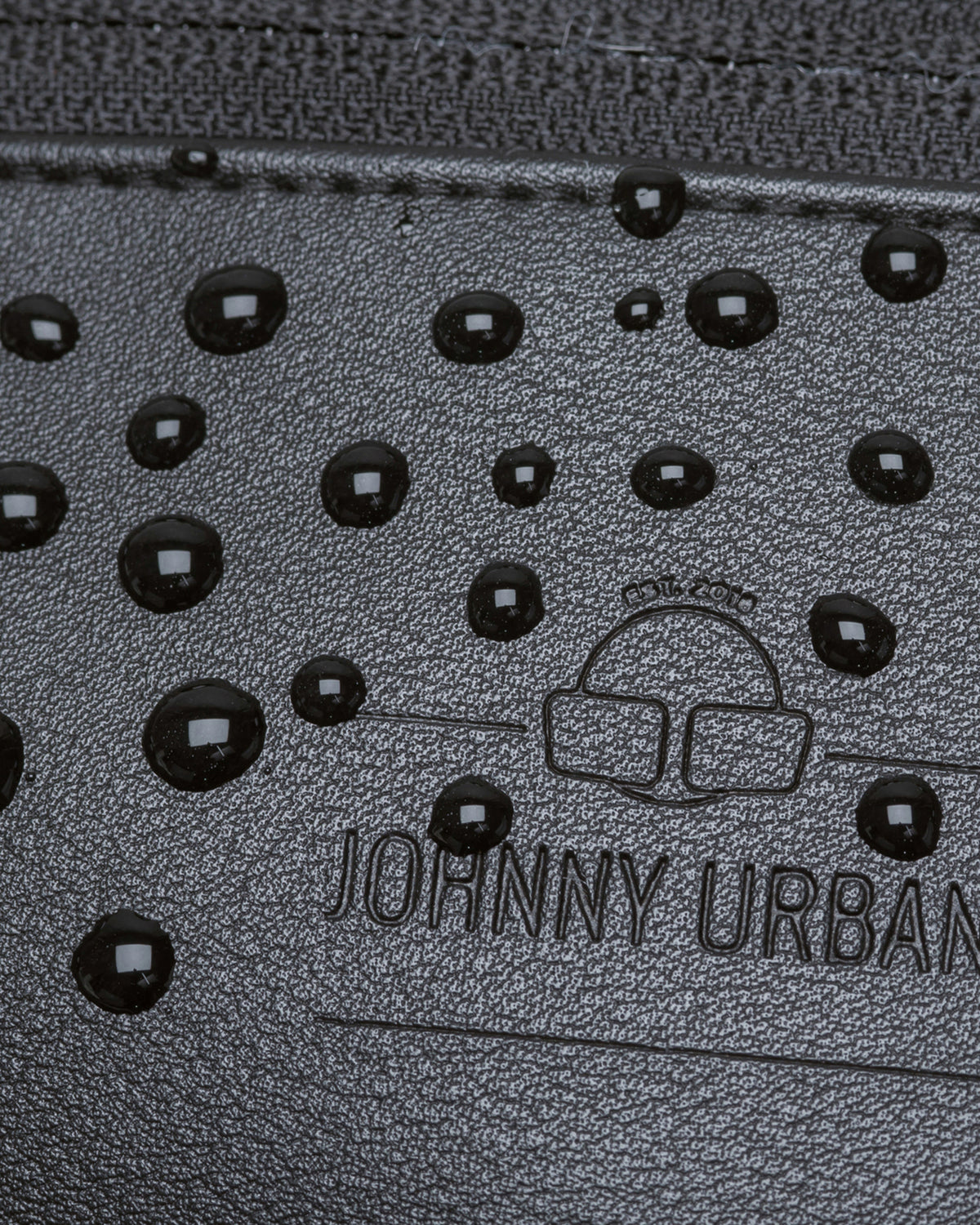 Nahaufnahme der wasserabweisenden schwarzen Kunstleder-Bauchtasche 'Toni' von Johnny Urban mit Wasserperlen auf der Oberfläche