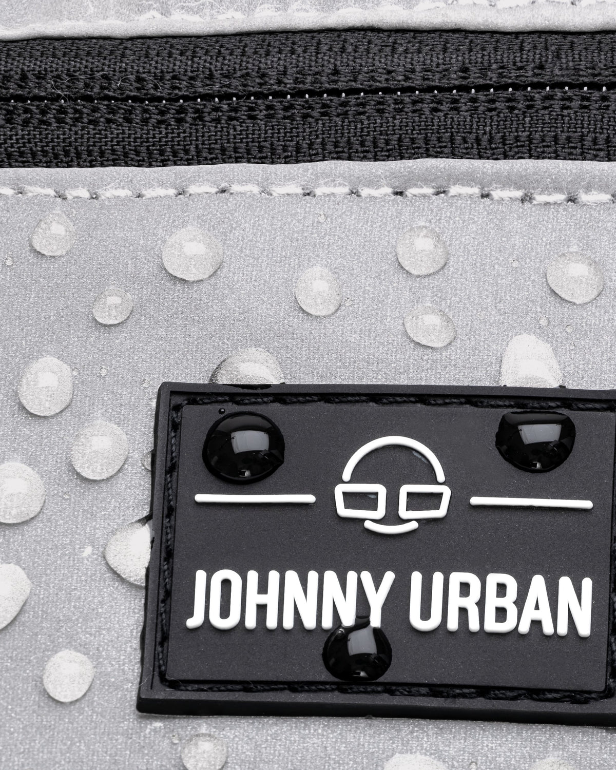 Nahaufnahme der reflektierenden, wasserabweisenden Bauchtasche ‚Erik Small‘ von Johnny Urban mit Logo und Wasserperlen