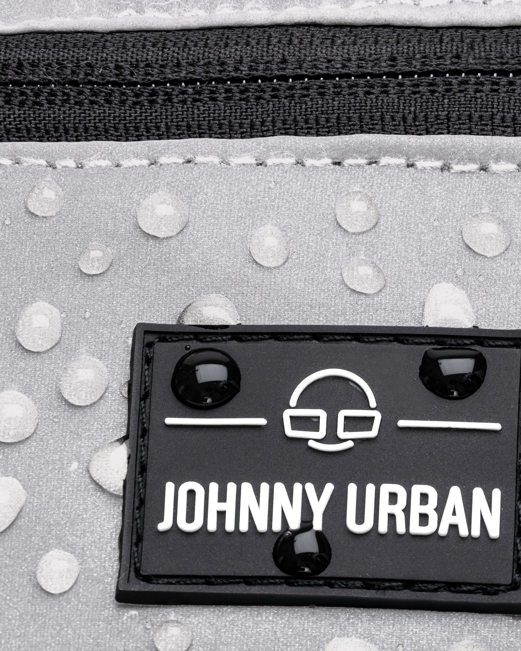 Nahaufnahme der reflektierenden, wasserabweisenden Bauchtasche ‚Erik Small‘ von Johnny Urban mit Logo und Wasserperlen