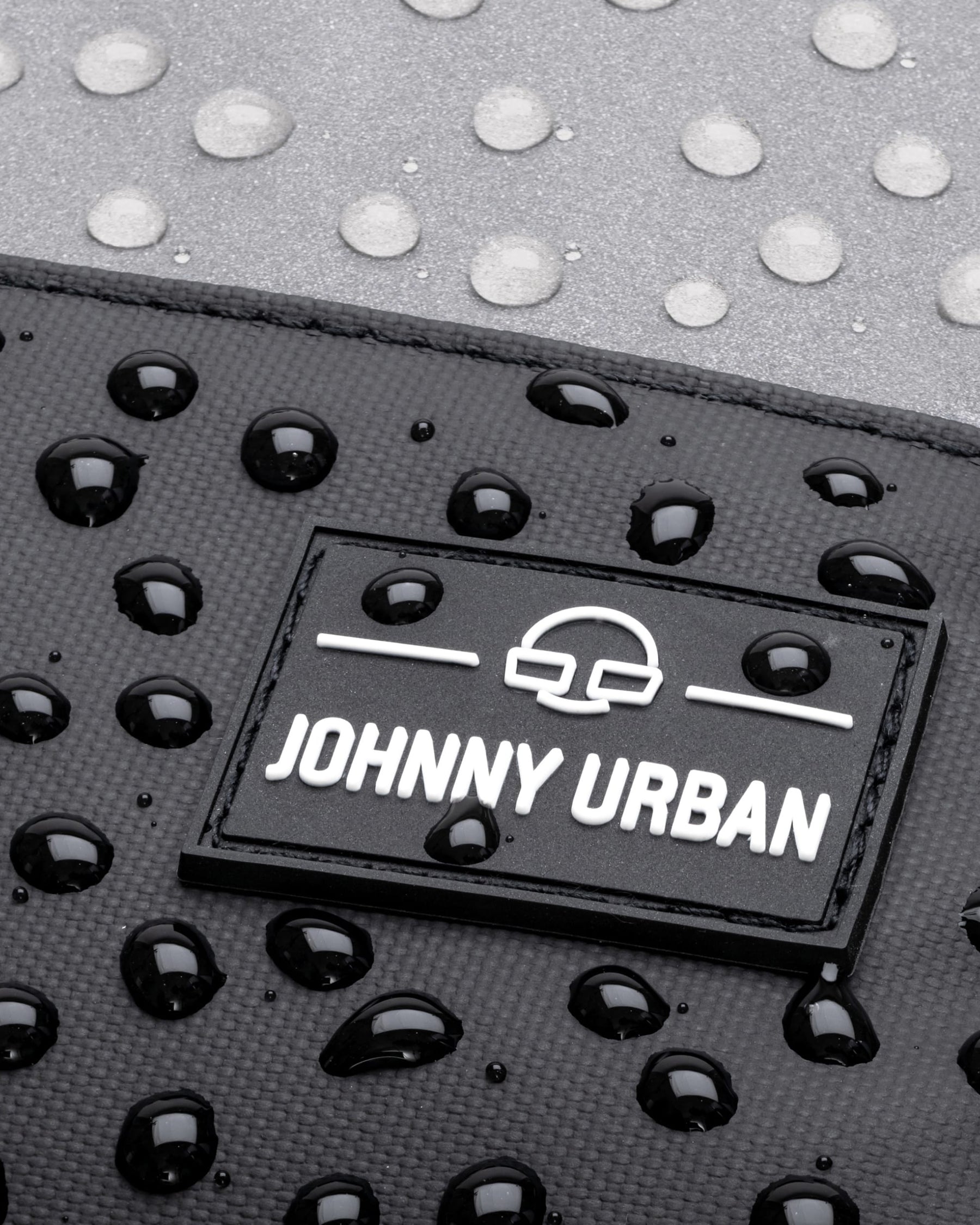 Nahaufnahme des wasserdichten Rucksacks 'Mika' mit Johnny Urban Logo und Wassertropfen auf der Oberfläche
