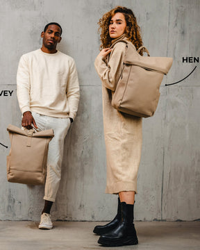 Mann hält hellbraunen Rolltop-Rucksack 'Harvey', Frau trägt hellbraunen Rolltop-Rucksack 'Henry' von Johnny Urban