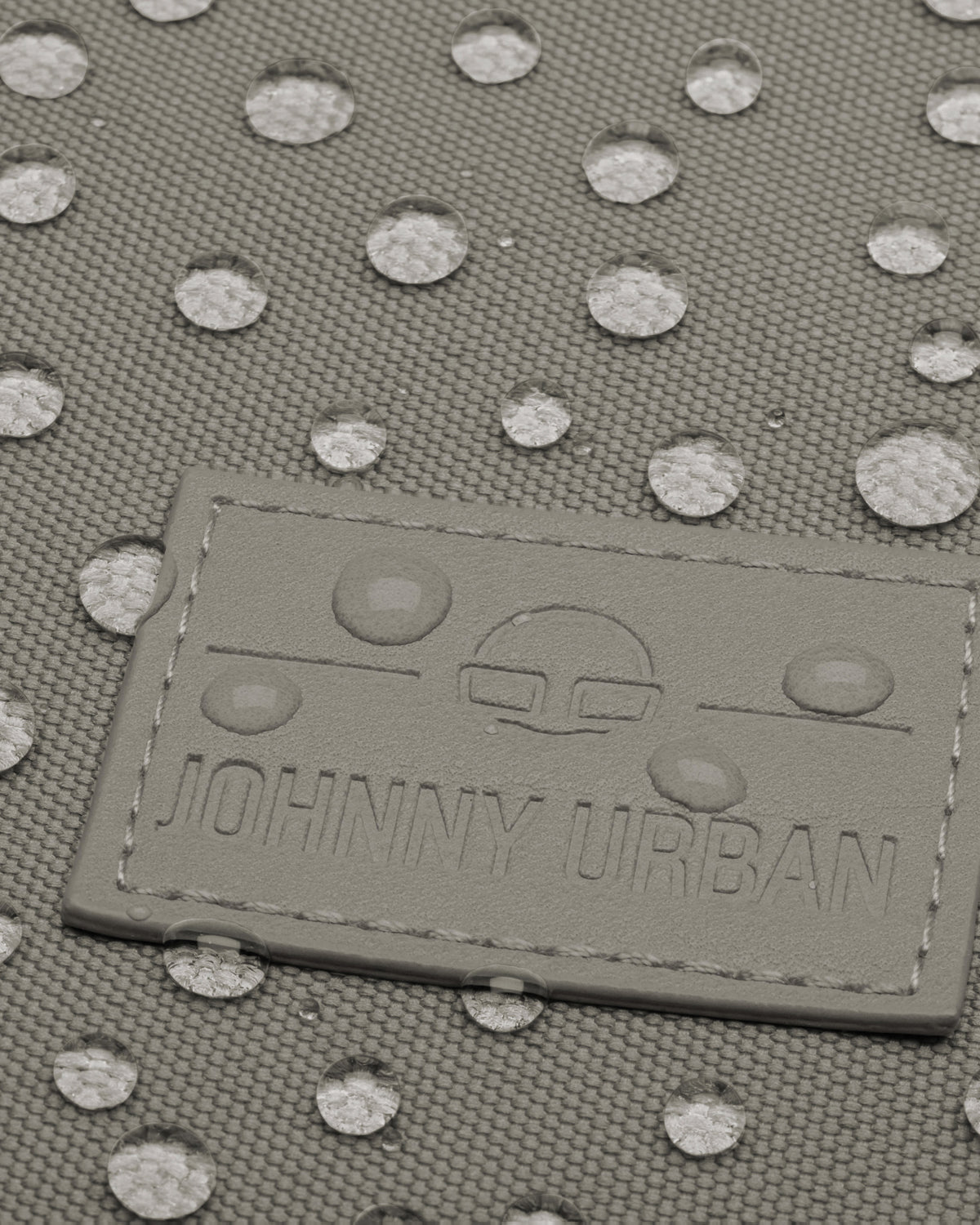 Logo von Johnny Urban auf dem wasserabweisenden Stoff des Rolltop Rucksacks Robin Medium in desert grey