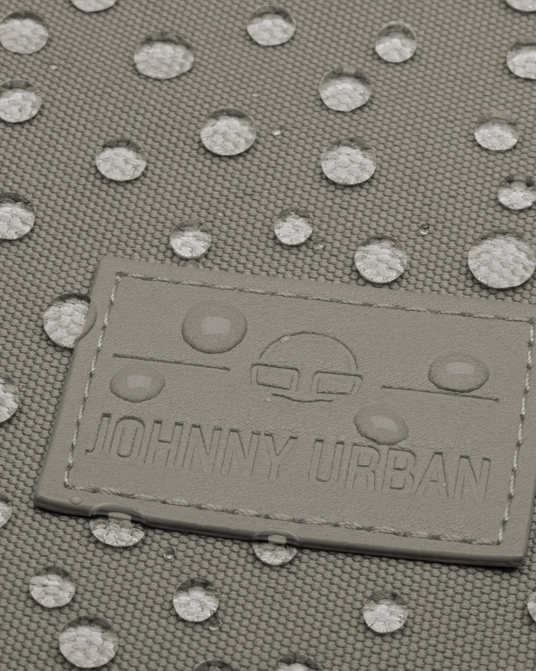 Logo von Johnny Urban auf dem wasserabweisenden Stoff des Rolltop Rucksacks Robin Medium in desert grey