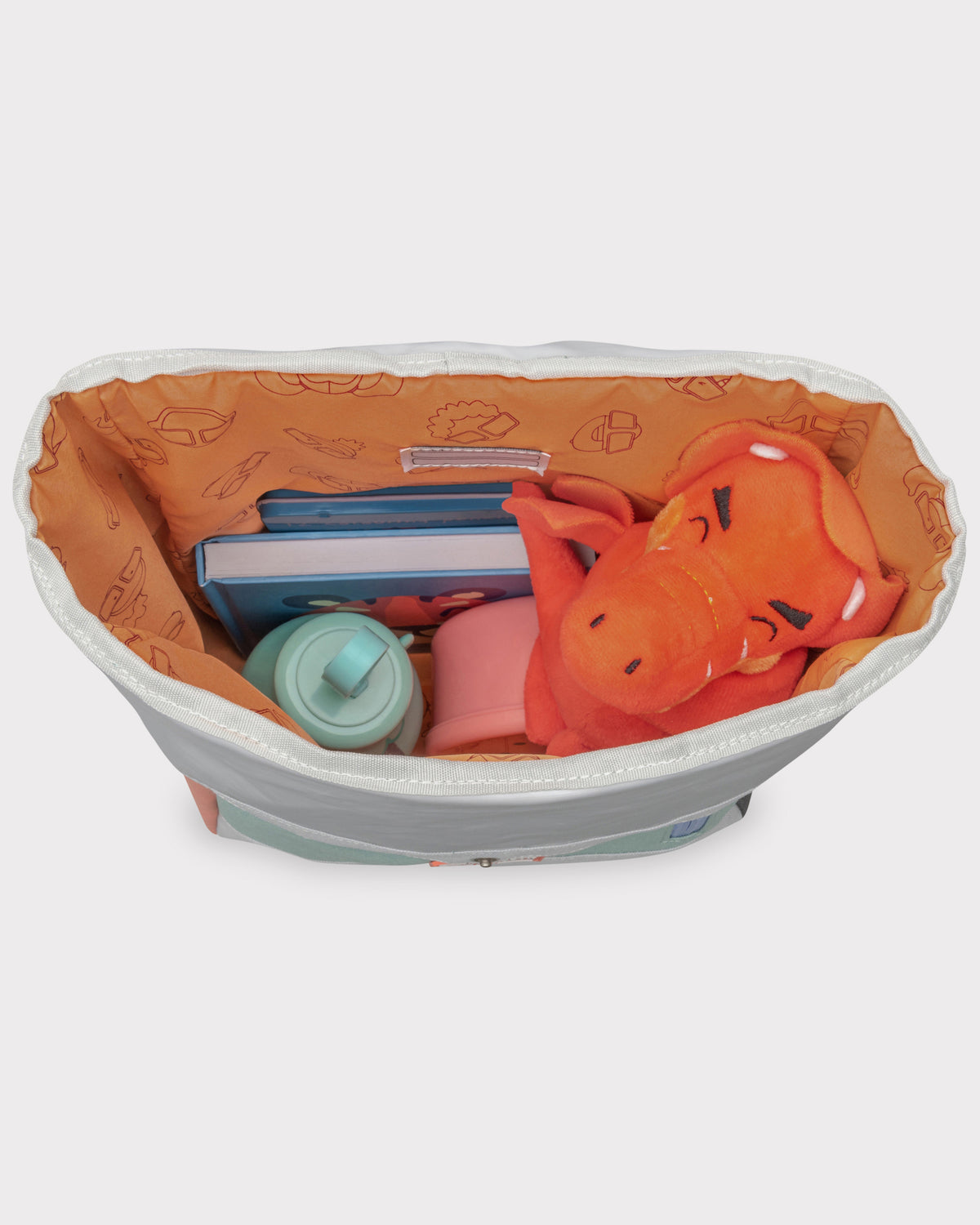 Offener Rolltop Kinderrucksack Aaron mit orangefarbenem Innenfutter, gefüllt mit blauen Büchern, rotem Drachenplüsch, Trinkflasche und Lunchbox
