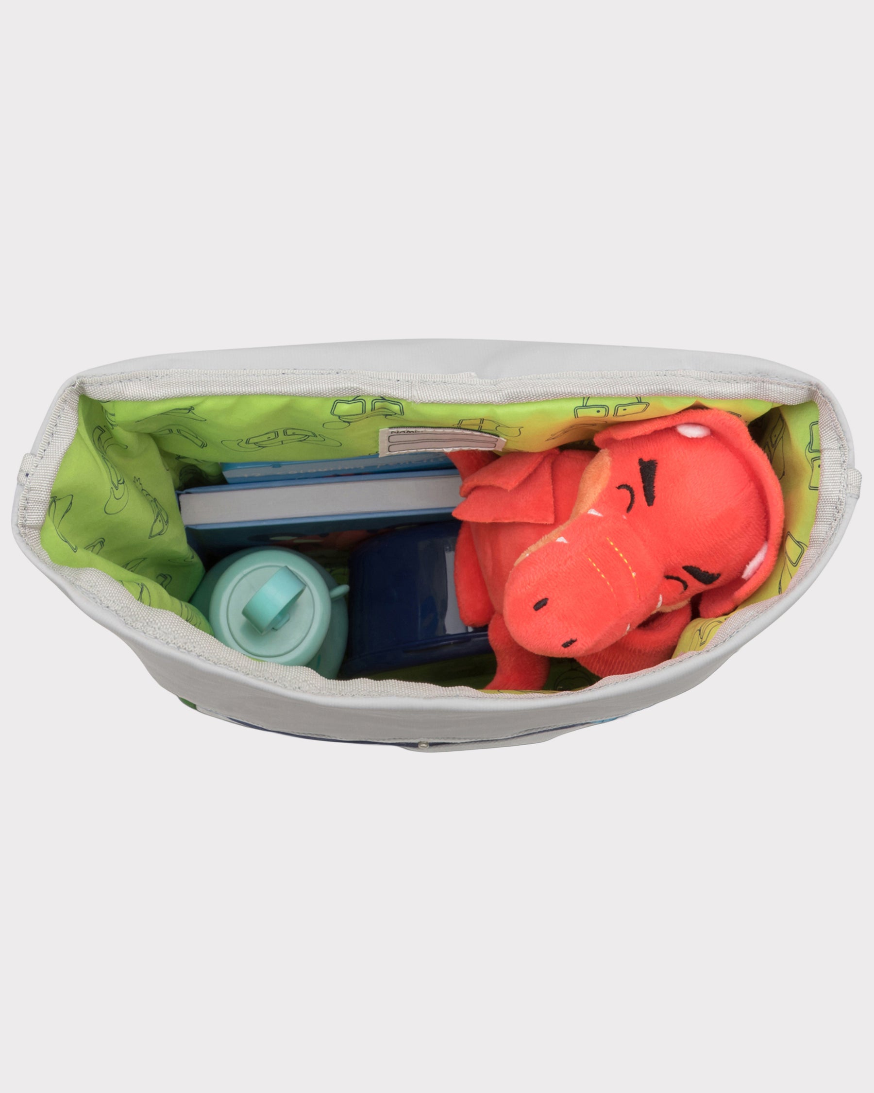 Blick in den Rolltop Kinderrucksack 'Aaron' mit grünem Innenfutter, rotem Stofftier Drachen, Wasserkunststoffflasche und Büchern