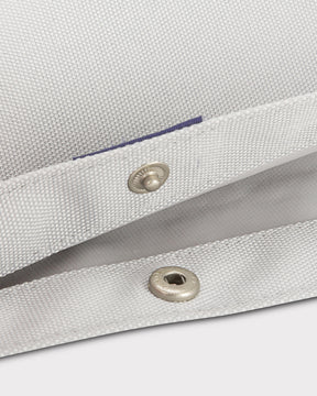 Nahaufnahme des hellgrauen Textilstoffs und Metall-Druckknopfverschlusses des Rolltop Kinderrucksacks 'Aaron'
