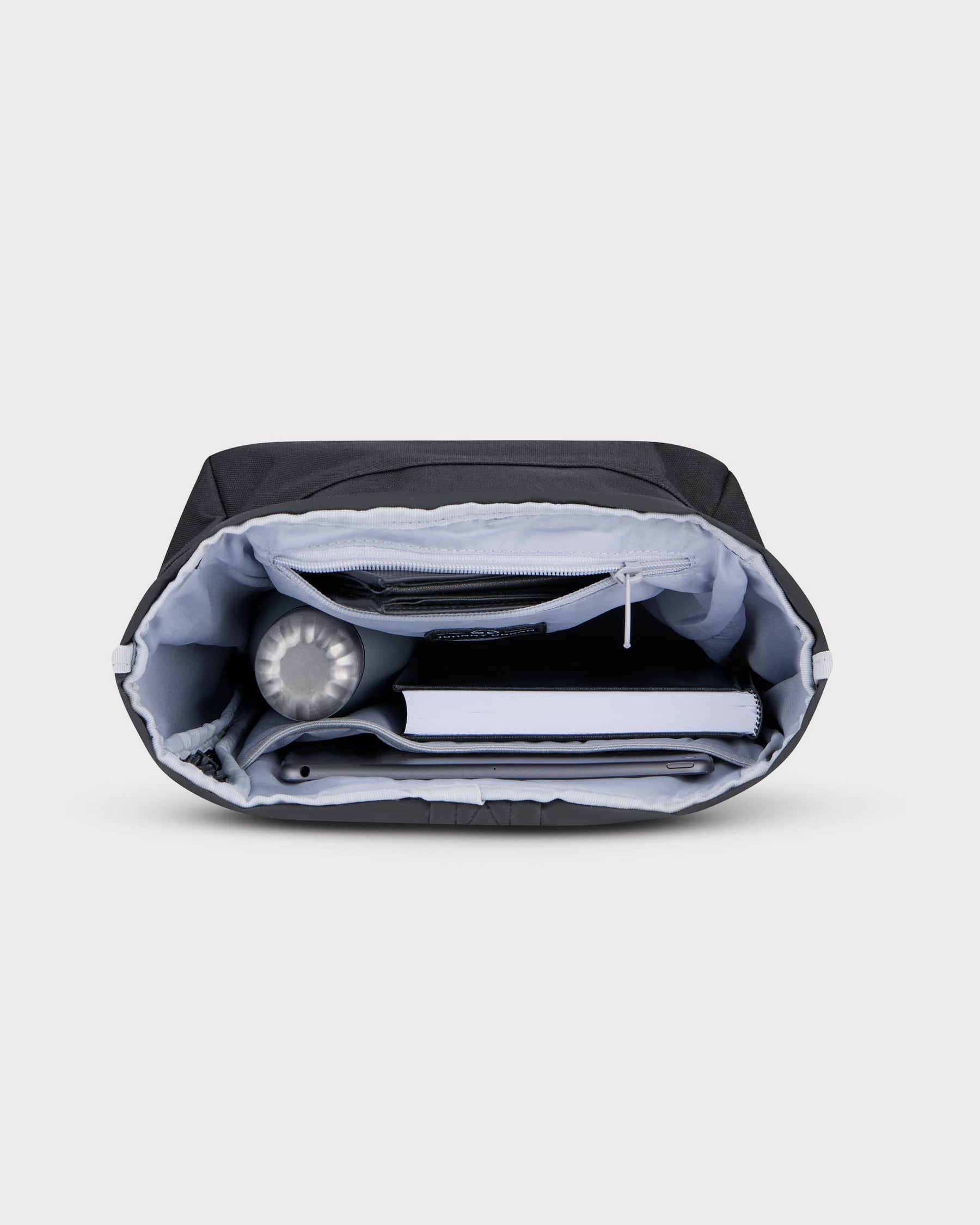 Rolltop Rucksack Robin Small in Schwarz mit organisiertem Innenraum, gefüllt mit Wasserflasche, Buch und Tablet