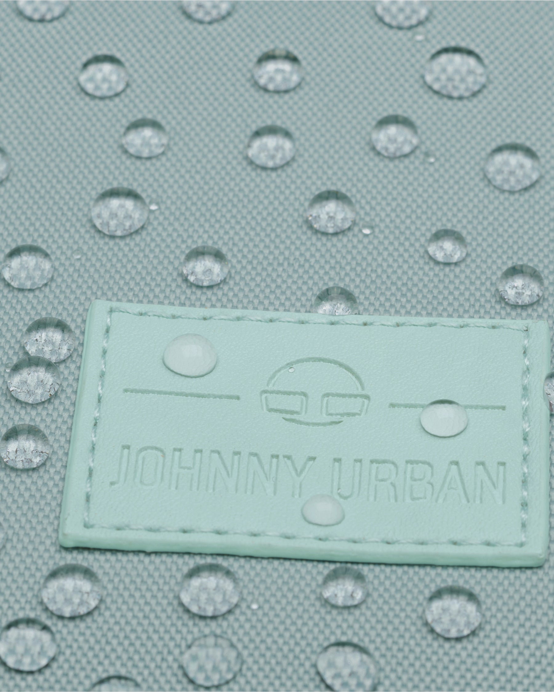 Nahaufnahme des mintgrünen Johnny Urban Rolltop-Rucksacks Robin Medium mit Wassertröpfchen auf dem wasserabweisenden Stoff