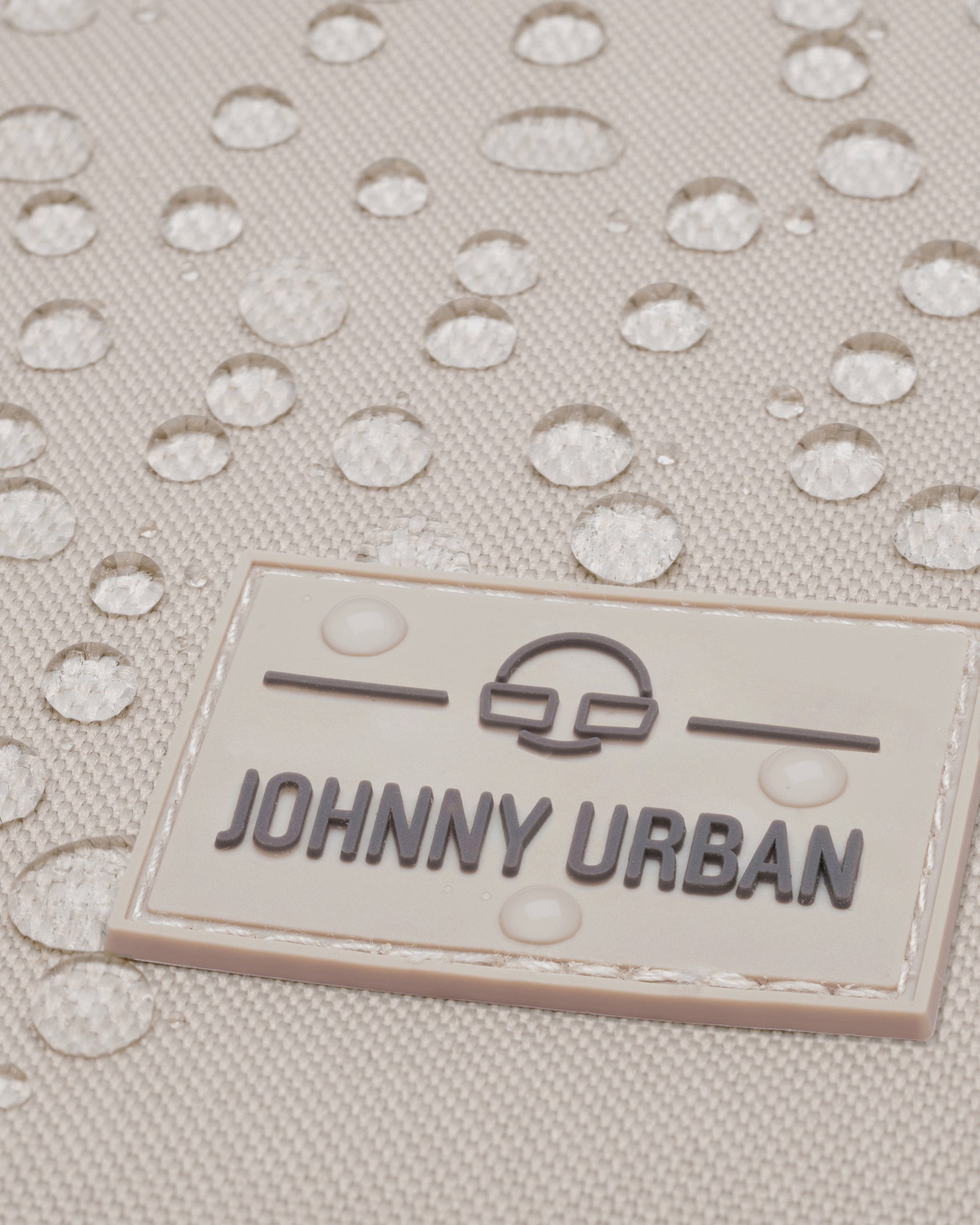 Beiger wasserabweisender Stoff mit Johnny Urban Logo und sichtbaren Wassertröpfchen