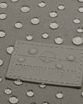 Nahe Aufnahme eines wasserdichten Johnny Urban Rolltop Rucksacks mit sichtbaren Wassertropfen auf dem grauen Gewebe
