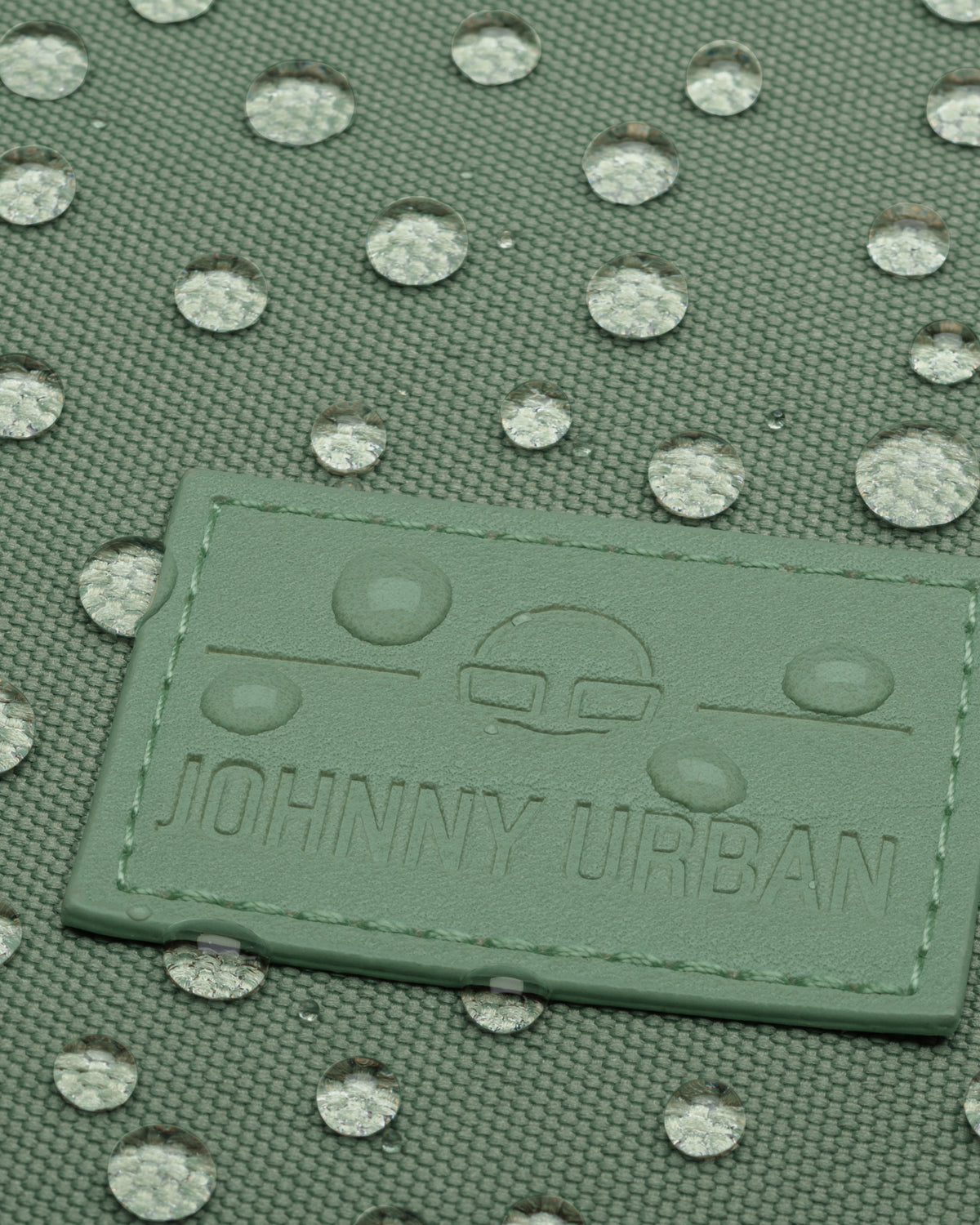 Nahaufnahme von Wassertröpfchen auf grünem, wasserdichtem Gewebe des Rolltop Rucksacks 'Robin Large' von Johnny Urban