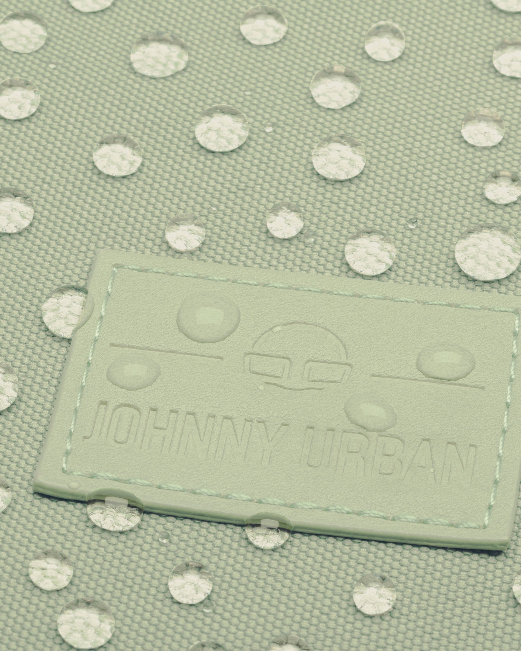 Nahaufnahme des limefarbenen Johnny Urban Rolltop Rucksacks mit wasserabweisenden Wassertropfen
