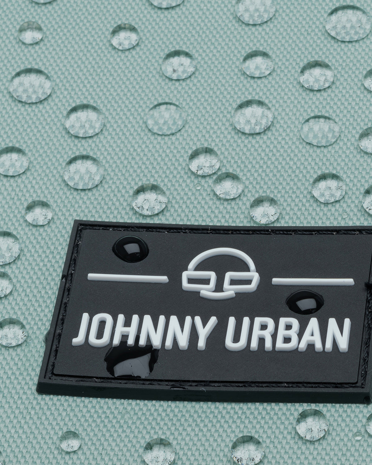 Wasserabweisender mintfarbener Stoff mit Johnny Urban Logo aus schwarzem Material und weißen Buchstaben