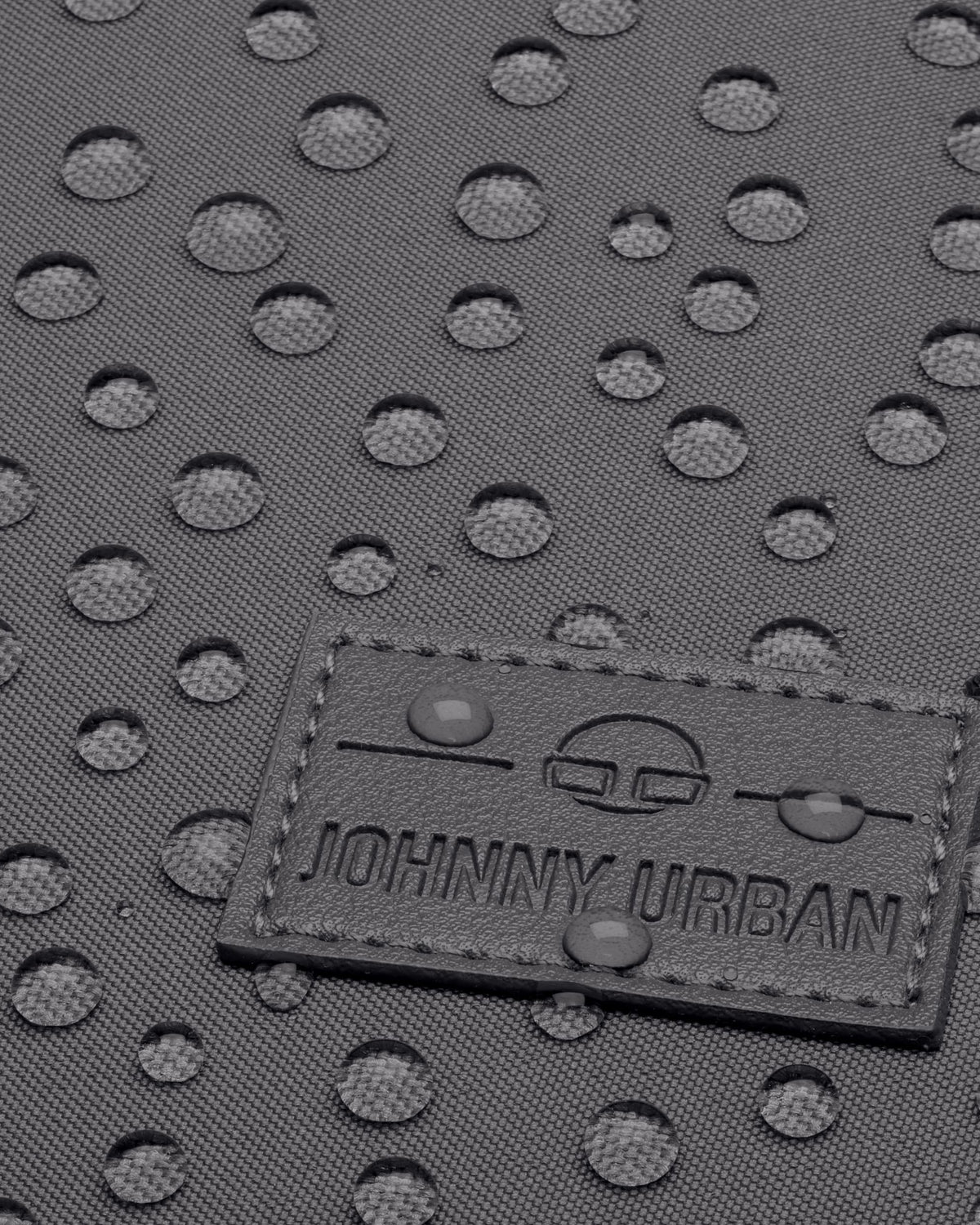 Nahaufnahme eines grauen wasserabweisenden Rucksacks Jona Medium mit Johnny Urban Logo und Wasserperlen