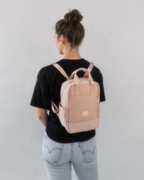 Frau trägt kleinen hellrosa Rucksack 'Jona Small' mit Taschen, schwarzes T-Shirt, helle Jeans