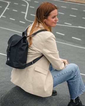 Frau sitzt auf Straße mit kleinem schwarzen Rucksack Damen 'Romy' von Johnny Urban