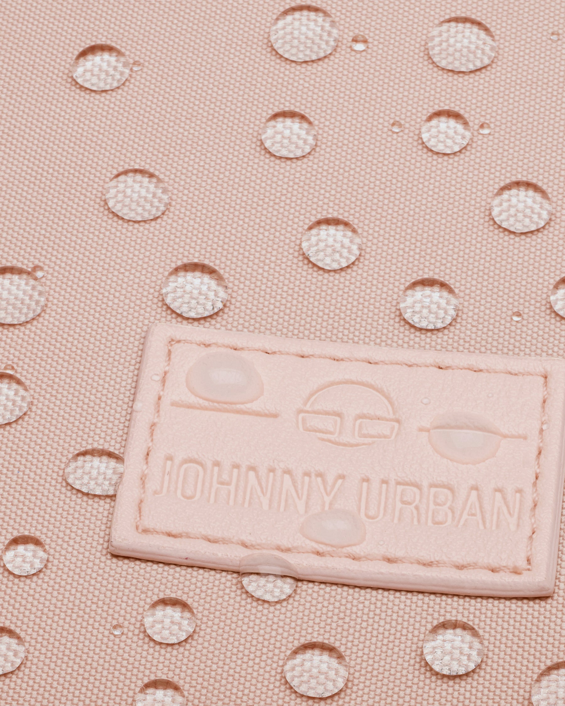 Nahaufnahme eines wasserabweisenden, rosa Stoffes mit Johnny Urban Logo-Patch