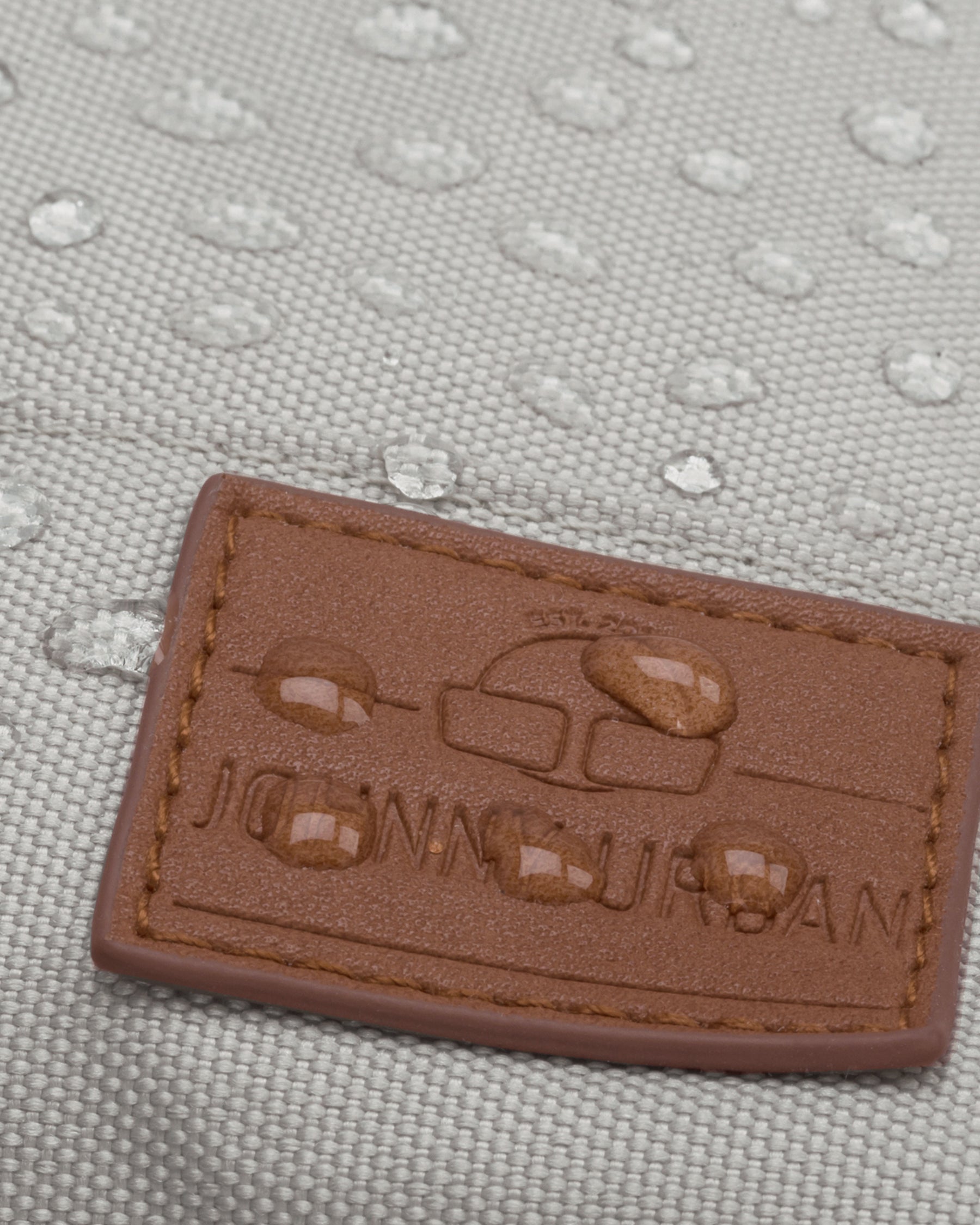 Wasserabweisender beiger Rucksack 'Mia' mit braunem Johnny Urban Logo-Patch und Wassertröpfchen darauf